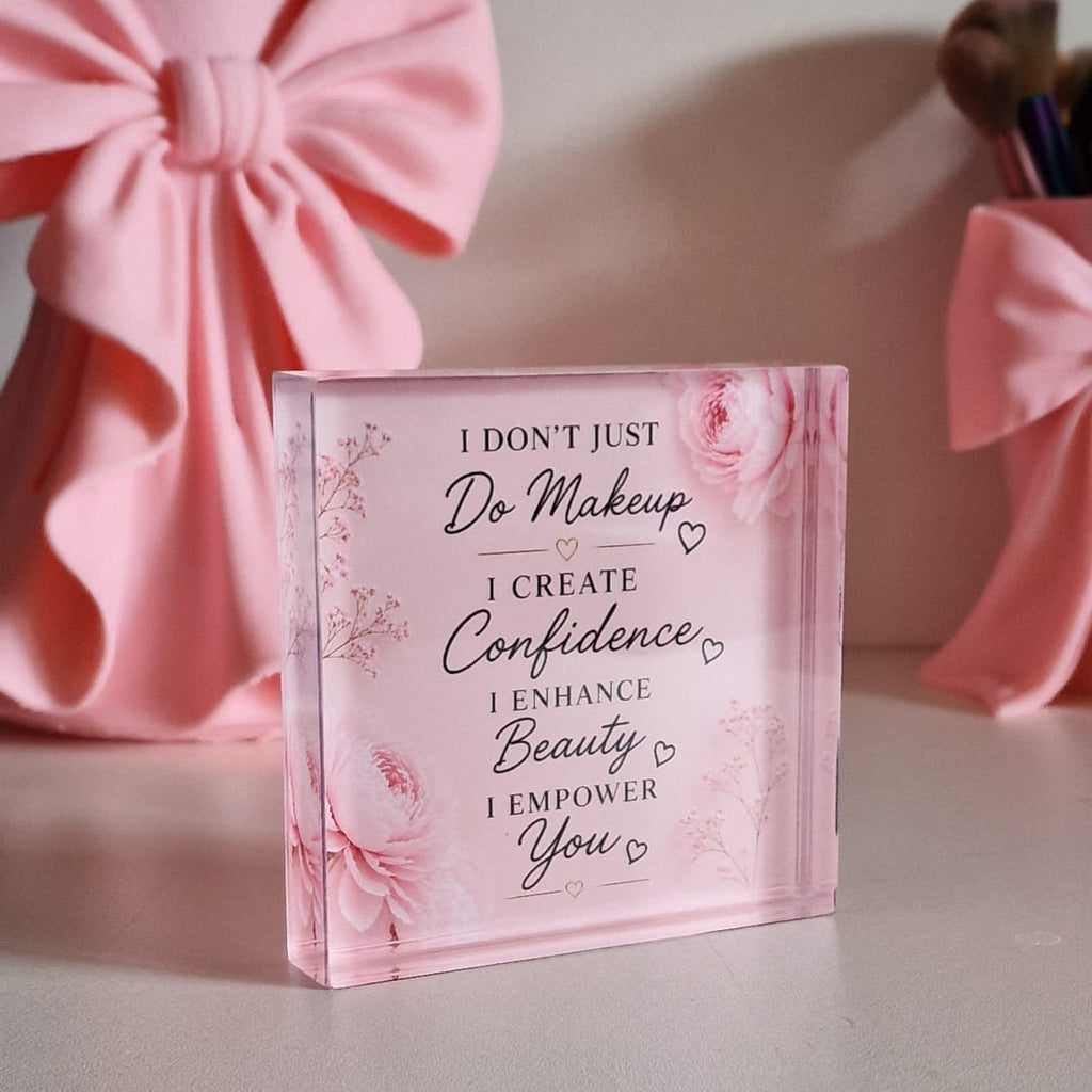 Pink decorative block with motivational quote on a light surface with pink bows in the background