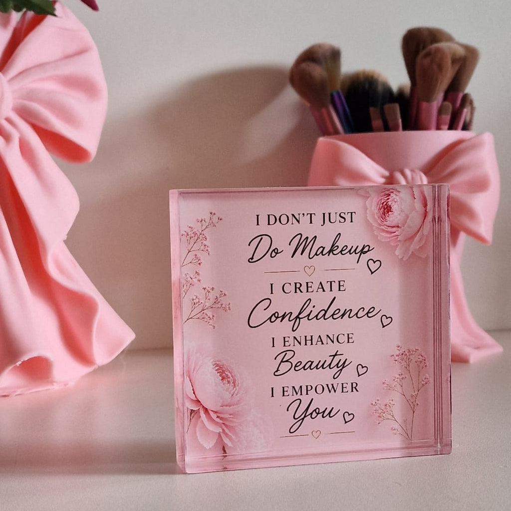 Pink makeup bag with text and makeup brushes on a white surface