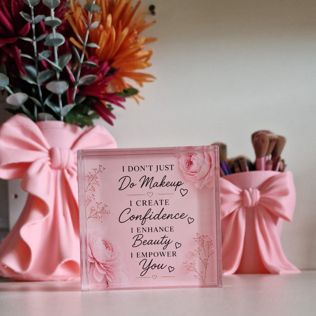 Pink decorative box with motivational quote, flowers, and small dog figurine on a white surface.