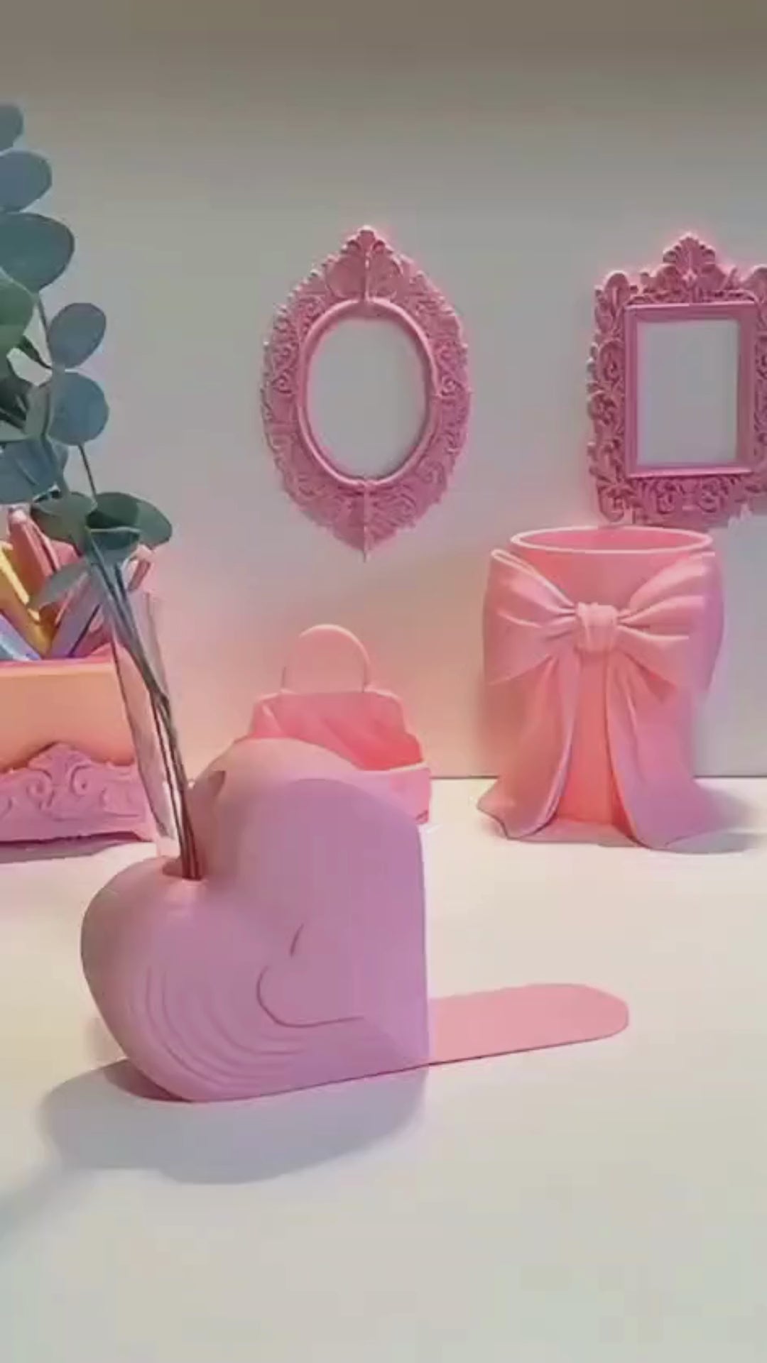 Pink heart bookend that doubles as a test tube vase, styled on a desk with books; romantic shelf decor and Valentine’s gift for book lovers.