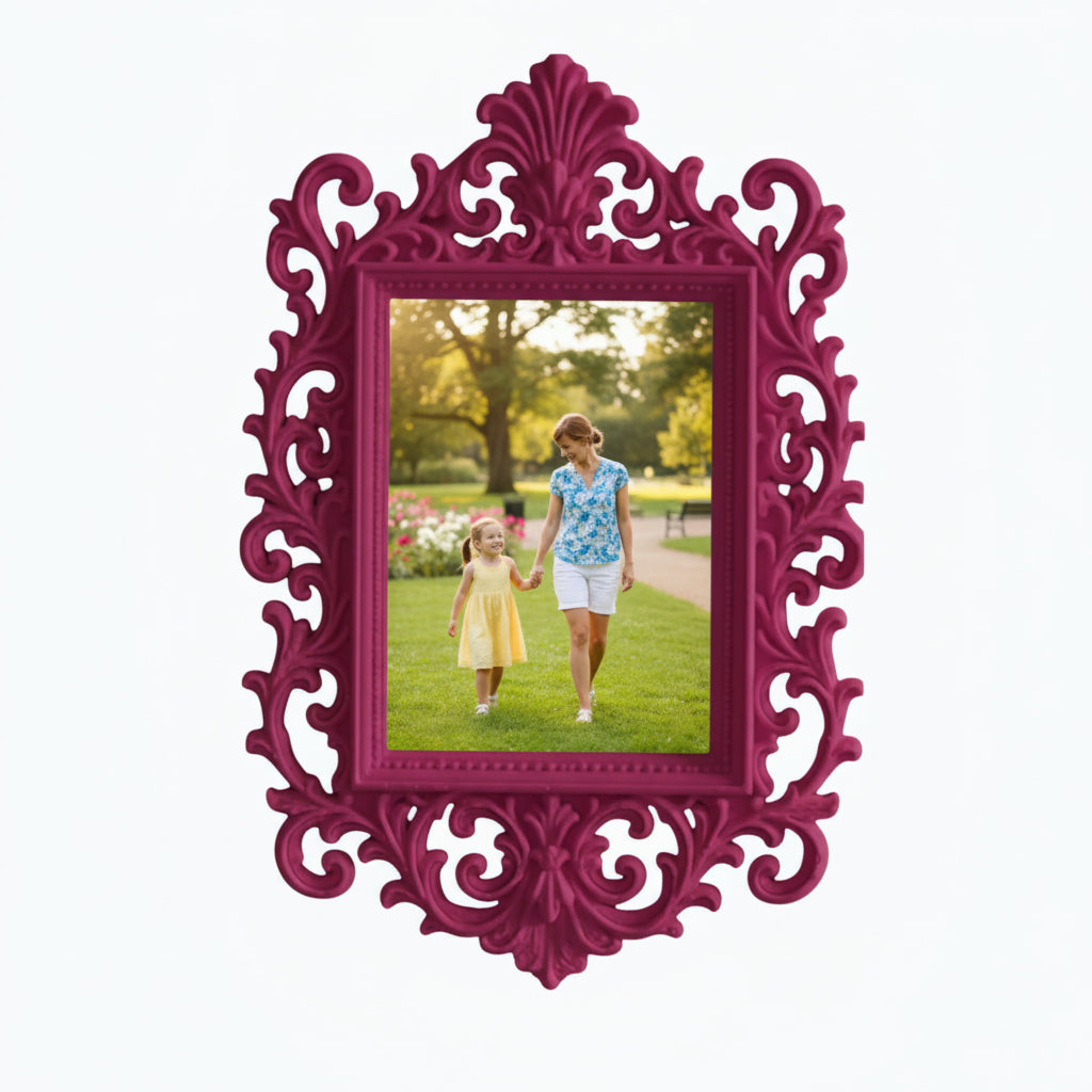 May include: A decorative pink picture frame with an elaborate, swirling design. The frame contains a photograph of a woman and child in a park. The frame is on a white shelf, with pink flowers and a candle.