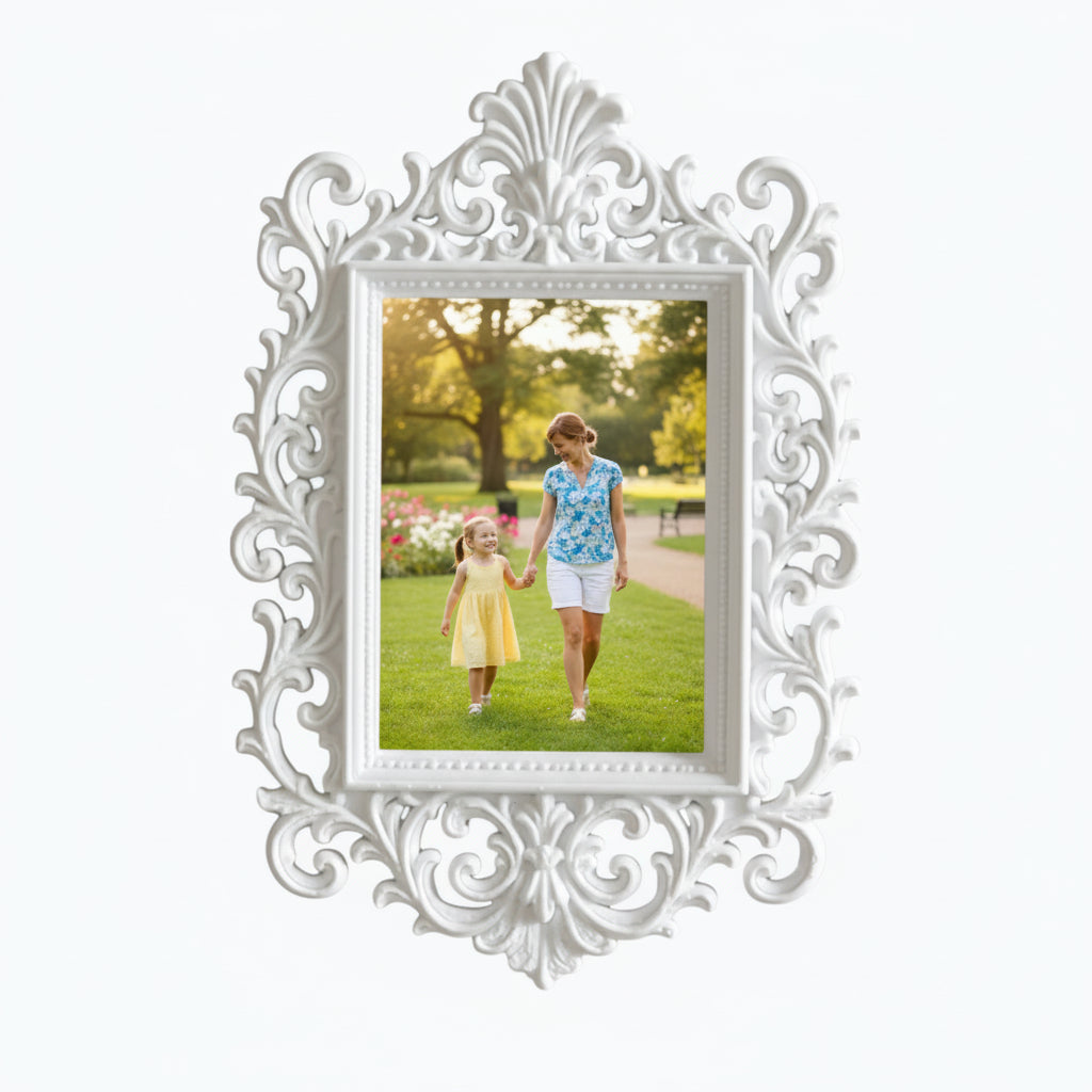 May include: A decorative pink picture frame with an elaborate, swirling design. The frame contains a photograph of a woman and child in a park. The frame is on a white shelf, with pink flowers and a candle.